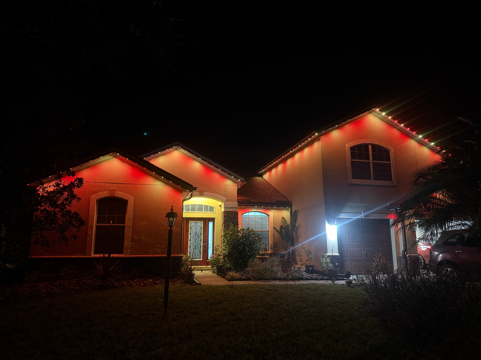 Home with permanent color-changing roofline lights set to red and white with matching uplighting