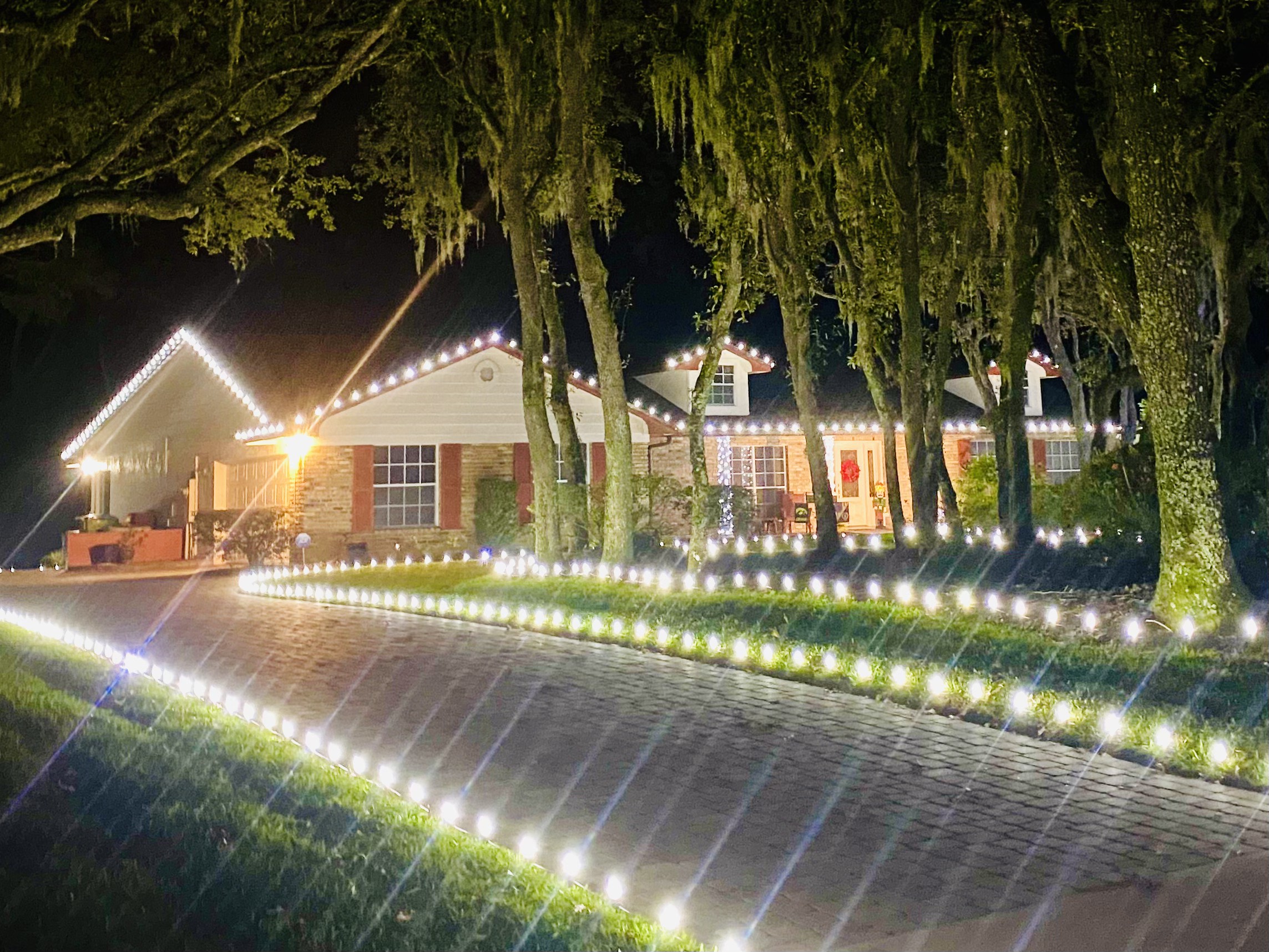 Brick home with crisp roofline C9 lights and a fully outlined driveway of pathway lights