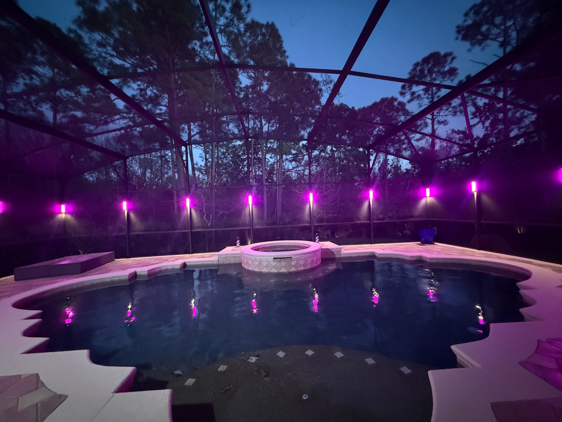 Pool enclosure lit in magenta with color-changing permanent lighting