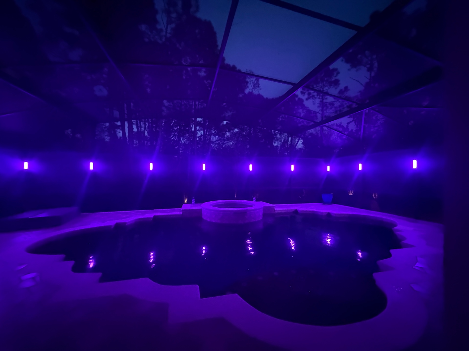 Pool enclosure illuminated in violet with permanent outdoor lights