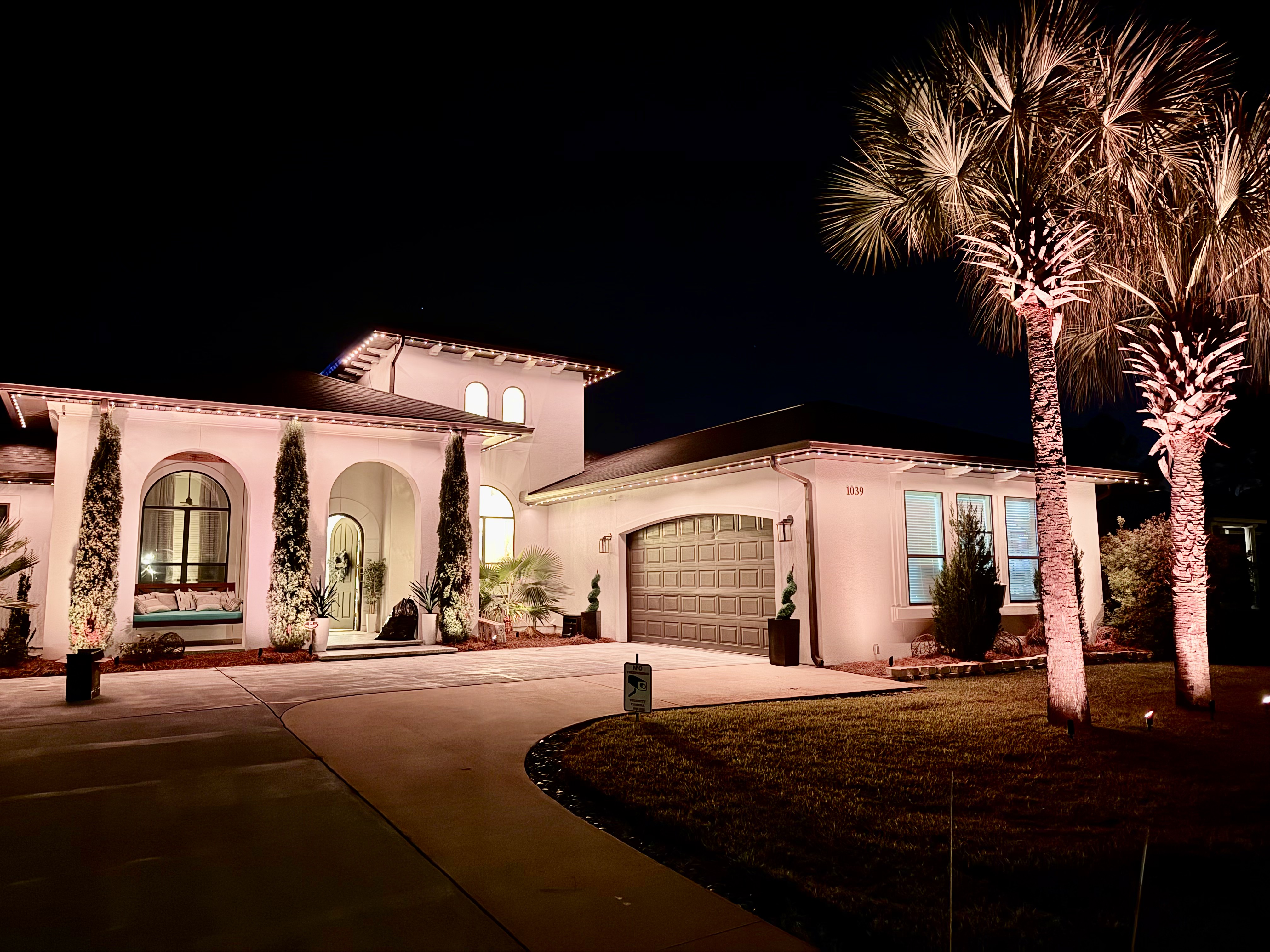 Modern home with warm architectural lighting and illuminated palm trees