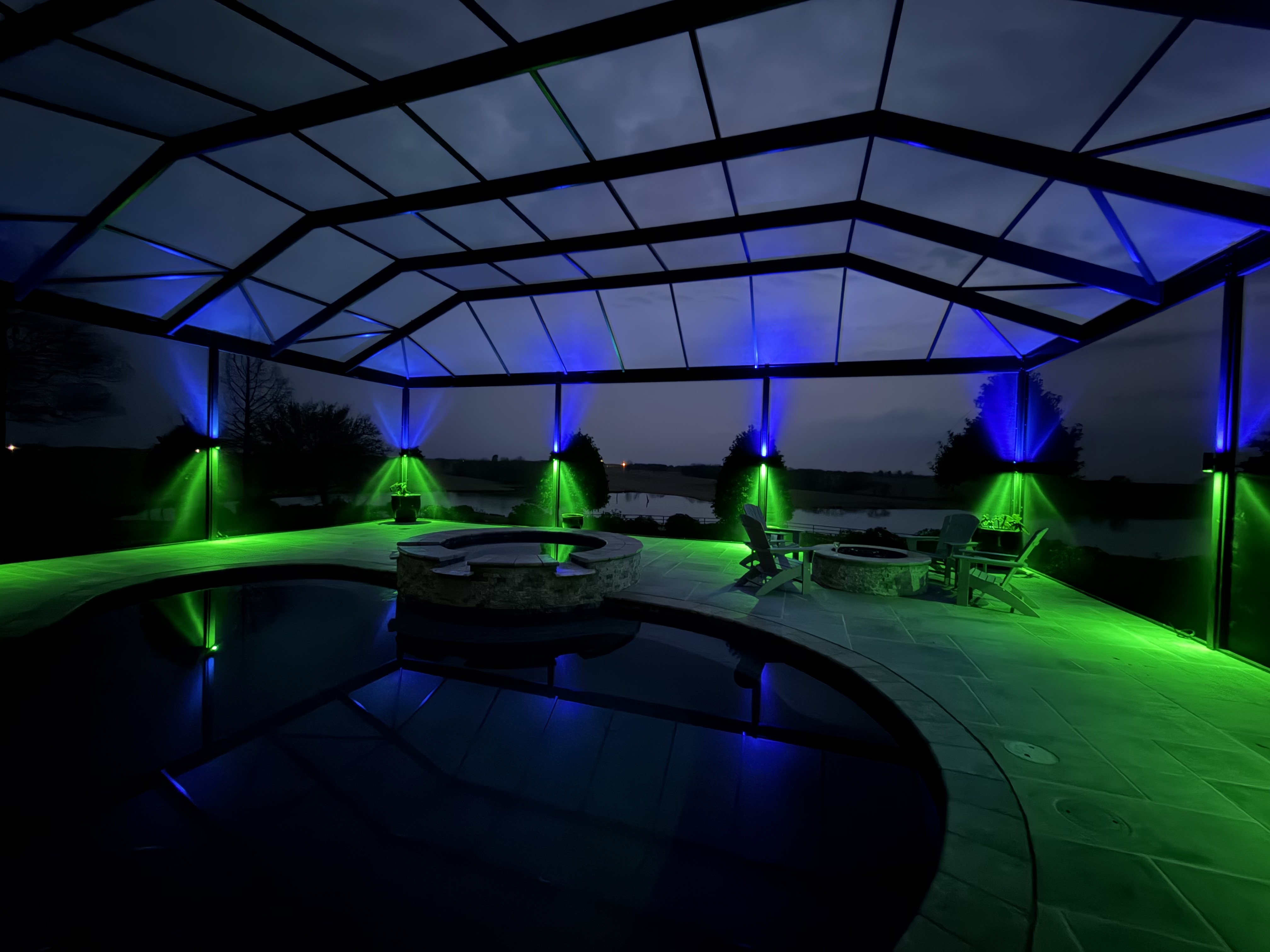 Screened pool deck lit in blue and green with permanent accent lighting